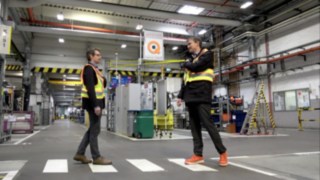 Covid-19 Ansteckungsgefahr verringern - die Linde Sicherheitsdistanzweste sorgt für den richtigen Abstand Zwei Werksarbeiter mit der Sicherheitsdistanzweste von Linde begegnen sich mit sicherem Abstand