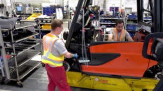 Auch in der Produktion heißt es Abstand halten für die Gesundheit - mit der Secure Distance Vest von Linde Zwei Mitarbeiter in der Produktion halten sicheren Abstand dank Distanzweste von Linde