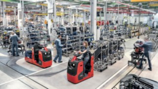 Schlepper mit mehreren Warenträgern steigern die Produktivität in der Produktsversorgung. Schlepper mit mehreren Warenträgern transportieren Bauteile an die Produktionslinie.