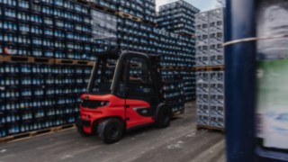 Wir bieten Ihnen die passende Sicherheitslösung für Ihre Intralogistik. Der Linde E-Stapler X30 transportiert Getränkekisten durch einen schmalen Gang im Außenlager.