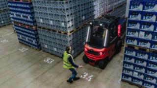 Der Linde Reverse Assist Radar senkt das Unfallrisiko bei der Rückwärtsfahrt. Ein Linde E-Stapler fährt rückwärts aus einem Gang heraus, während ein Fußgänger dort gerade vorbeiläuft.