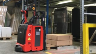 Der L-MATIC von Linde Material Handling unterstützt das Kommissionier-Team vor Ort. L-MATIC von Linde Material Handling platziert eine Palette mit Paketen im Regal.