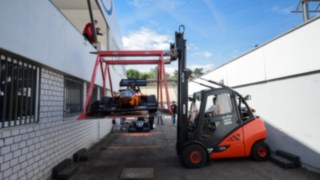 Linde Mietstapler befördert vorsichtig eine Rennwagen in einer extra dafür vorgesehen Vorrichtung Linde Mietstapler befördert vorsichtig eine Rennwagen
