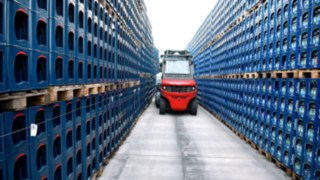 Der E-Stapler von Linde bietet ein Maximum an Arbeitssicherheit. Eine Linde E-Stapler umringt von Getränkekisten.