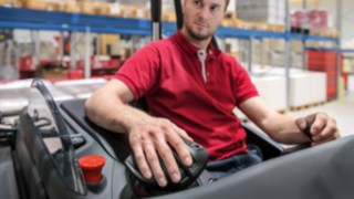 Durch die Armauflage erfolgen alle Steuerbewegungen aus dem Handgelenk heraus und belasten den Unterarm nicht unnötig. Mitarbeiter legt seine Hand auf den Multifunktionshebel von Linde Material Handling