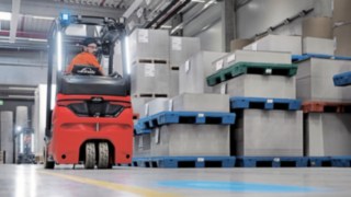 Ob vor- oder rückwärts: Die ergonomische Kabine minimiert die körperliche Belastung für den Fahrer. Ein Staplerfahrer fährt rückwärts mit dem Linde E-Stapler durchs Lager.
